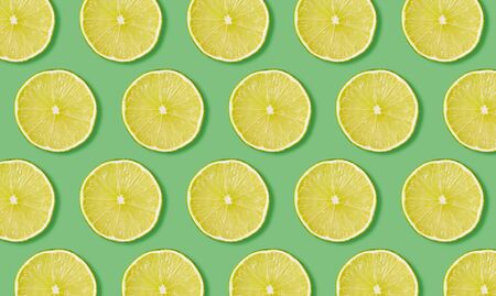 Top view of fruit pattern from slices of lime on green background