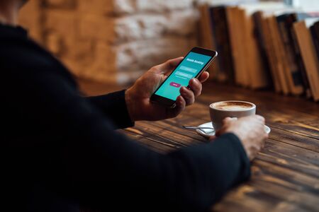 Man holds mobile phone with internet banking and coffee cupの写真素材