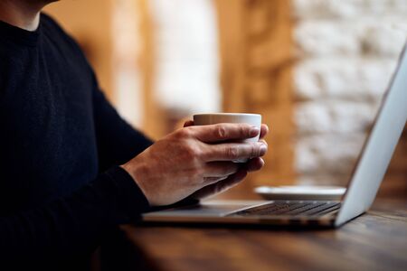 Man with cup of coffee in cafe and laptopの写真素材