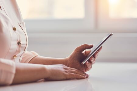 Woman using mobile phone while sitting in officeの写真素材