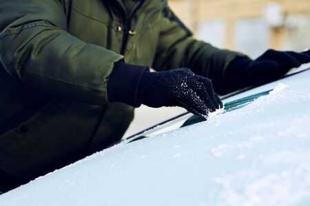 Close up of man scraping ice from the windshield of a carの写真素材