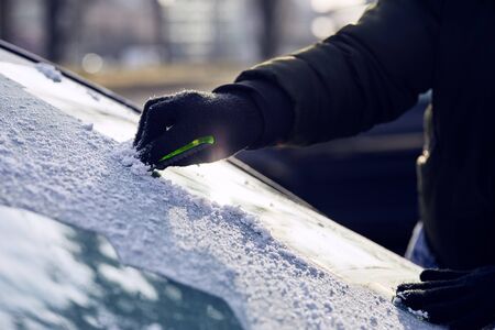 Man scraping ice from the windshield of a carの写真素材