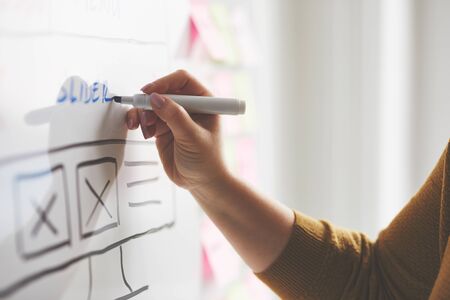 Female web developer with marker sketching website on whiteboard