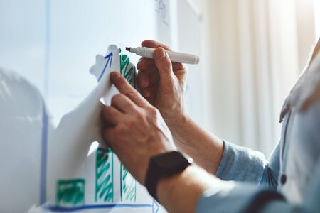 Man draws graph with marker on white board at officeの写真素材