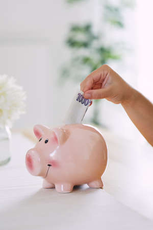 The woman puts a thousand Czech crowns into the money box