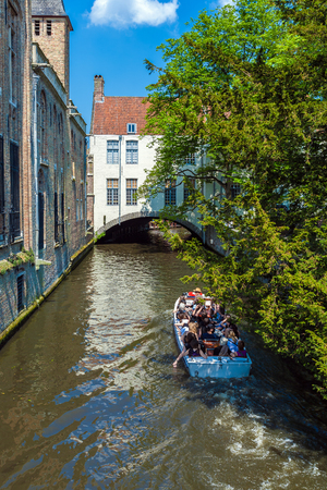 BRUGES, BELGIUM - APRIL 6, 2008: Tourists float on a boat through the Dijver channel near vintage homesのeditorial素材