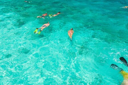 Tourists involved in snorkeling in shallow ocean water near tropical island, Maldivesの写真素材