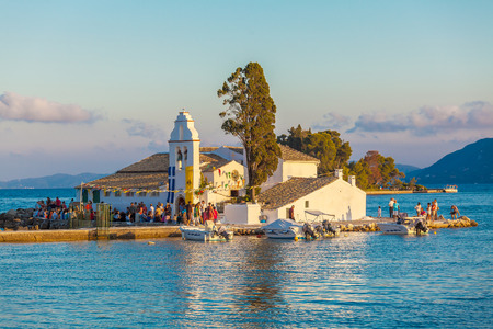 CORFU, GREECE - JULY 2, 2011: Tourists walking in front of Vlacherna monastery at sunset, decorated in honor of the patronal feastのeditorial素材
