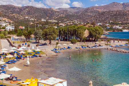 AGIOS NIKOLAOS, GREECE - AUGUST 2, 2012: Tourists swim in the Mediterranean sea on the beach of one of the hotels with plenty of sun loungers and parasolsのeditorial素材