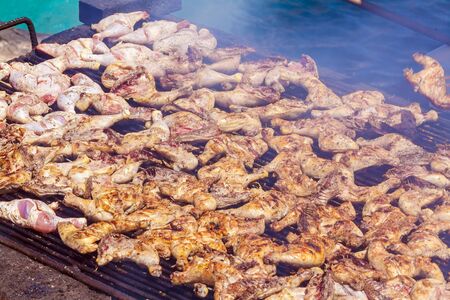 BBQ chicken legs roasting on the grill for a large group of peopleの写真素材