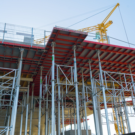 Construction of a shopping mall with the help of a yellow tower crane, a frame with iron pipes and a...