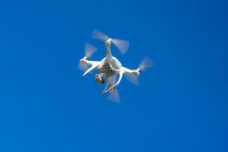 White flying air drone quadrocopter against the blue sky