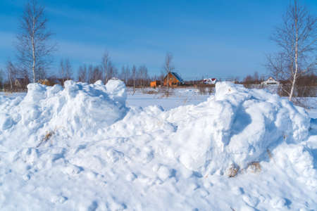 Huge piles of snow after the work of a tractor to clear rural roads in winter the consequences of heavy snowfallの写真素材