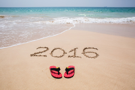 holiday on a sandy beach with 2016 digits written on sand