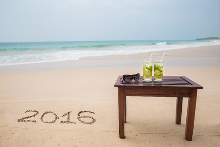 holiday on a sandy beach with 2016 digits written on sandの写真素材