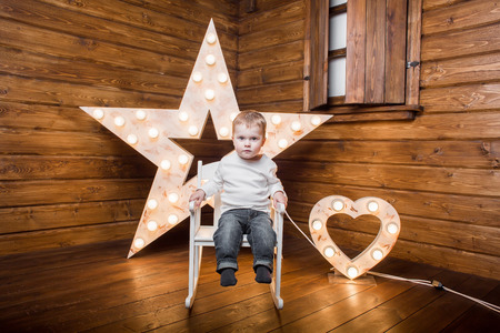 a boy sitting on a chair inside a decorated wooden houseの写真素材