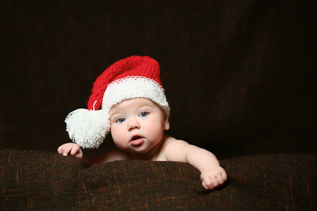 a christmas baby with an open mouth wearing a red and white christmas hatの写真素材