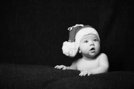 black and white photo of a christmas baby with an open mouth wearing a chrismas hatの写真素材