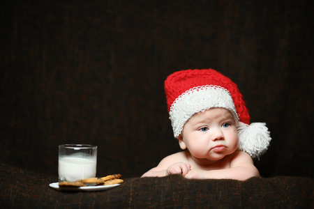 a displeased christmas baby with a glass of milk and biscuitsの写真素材