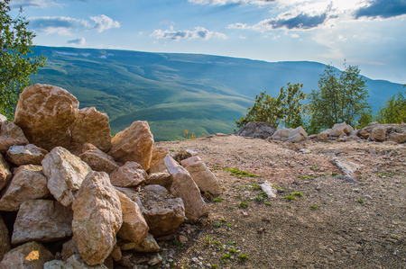 Pile of rocks and stones near cliff on sunset in mountain regionの写真素材