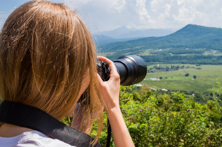 Young woman taking picture with professional camera outdoorの写真素材