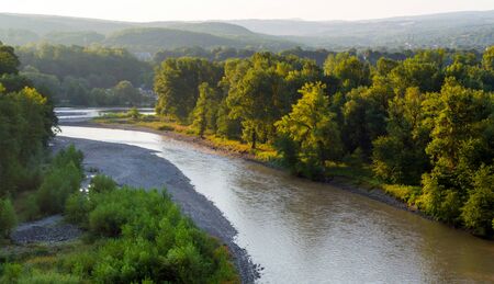 Bend of the mountain river. Dawn sun illuminates the trees on the shore.の写真素材