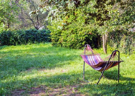 Colored hammock in green garden. Warm morning sunlight in summer.の写真素材