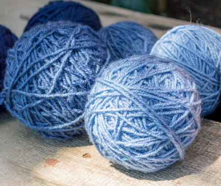 Violet skeins of wool on a wooden surface, in the light of the sunの写真素材