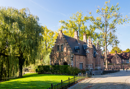 The cute old traditional brick house in Brugge. Willow tree near building. small Belgian townの写真素材
