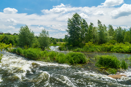 Flowing river stream of water in the rocks with blue sky. Water flows a torrent in the riverの写真素材