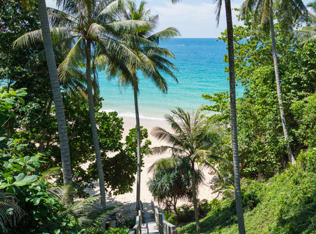 Old wooden down stairs to the beach, with palms around. Naithon beach, Phuket, Thailand