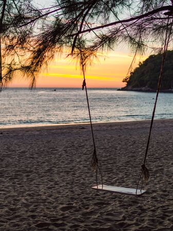 Swing on a tropical beach against the sun lightの写真素材