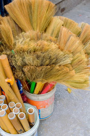 Old brooms in a plastic bucket on the street marketの写真素材