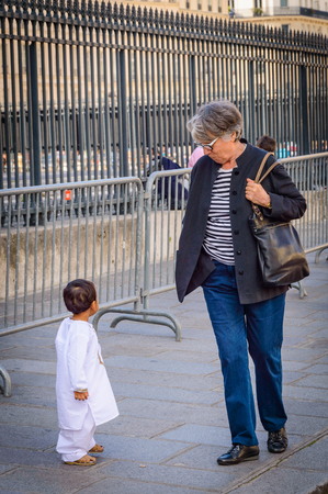A European woman looks at a child of Arab appearance, which is probably lost on the street. Paris, France, October 04, 2014.のeditorial素材