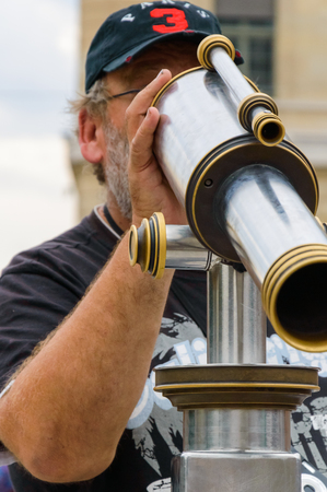 Tourist man look through the long street monocular scope on city landscapeのeditorial素材