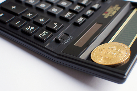 golden bitcoin coin on black calculator close up.の写真素材