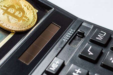 golden bitcoin coin on black calculator close up.の写真素材