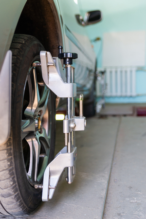 Car on stand with sensors on wheels for wheels alignment camber check in workshop of Service station.の写真素材