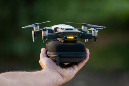 Russia, Sinyavskoe: August 20, 2018: DJI Mavic Air drone ready to start from case in men hand....