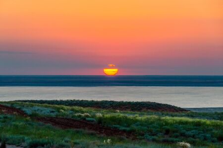 Beautiful bright red sunset over the lake and steppe.の写真素材