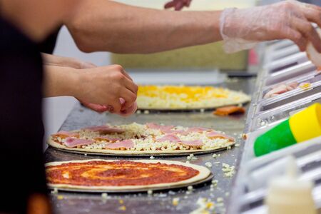 Cook in the kitchen putting the ingredients on the pizza. Pizza concept. Production and delivery of food.の写真素材