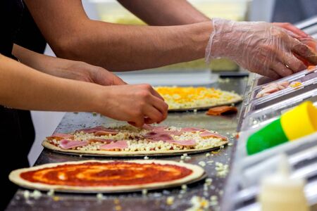Cook in the kitchen putting the ingredients on the pizza. Pizza concept. Production and delivery of food.の写真素材
