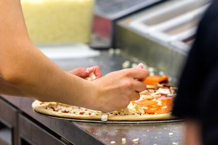 Cook in the kitchen putting the ingredients on the pizza. Pizza concept. Production and delivery of food.の写真素材