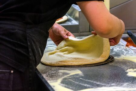 Cook in the kitchen putting the ingredients on the pizza. Pizza concept. Production and delivery of...