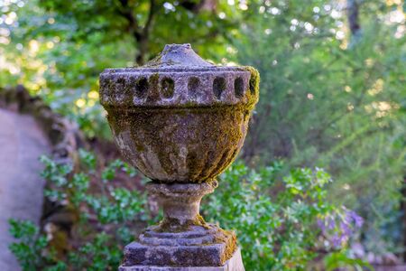 Garden decorative decoration among the greenery, an ancient granite vase stands on a pedestal in the Park.の写真素材
