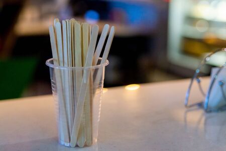 Wooden sticks in plastic cup for stirring sugar in coffee in cafeteria.の写真素材