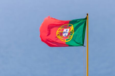 Flag of Portugal waving, against blue sky.の写真素材