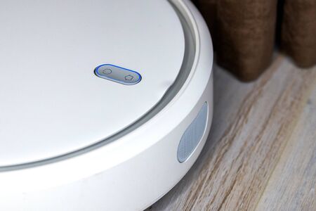 Smart home. Robot vacuum cleaner performs automatic cleaning of the apartment at a certain time. Close up view with selective focusの写真素材