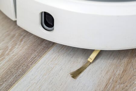 Smart home. Robot vacuum cleaner performs automatic cleaning of the apartment at a certain time. Close up view with selective focusの写真素材