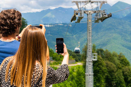 Girl taking pictures of cable car on mobile smartphone.